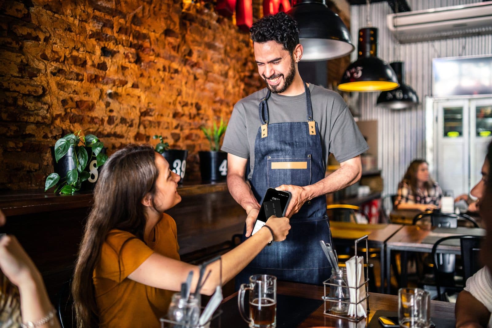 Server taking a tableside payment on a Shift4 handheld device